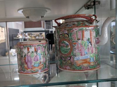 a glass shelf with two cups and a teapot on it