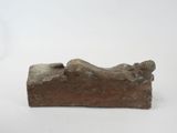 an old stone statue of a person laying down on a white surface