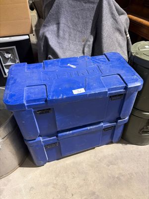 une boîte bleue posée par terre à côté d'une poubelle