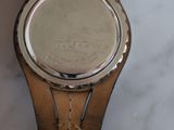 wrist of a person holding a watch on a marble surface