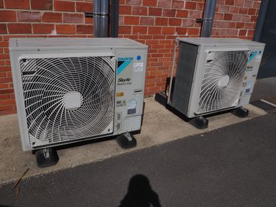 deux climatiseurs installés sur le côté d'un immeuble