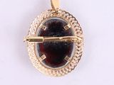 a gold brooch with a red stone in it