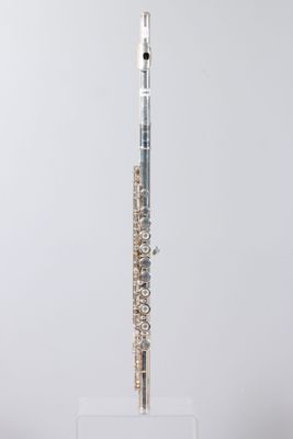 a silver flute on a clear stand against a white background