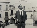 photographie en noir et blanc d'un homme en costume-cravate, debout devant un immeuble