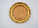 a close up of a coin in a gold frame on a white surface