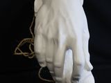 a white sculpture of a hand holding a string