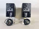 two black speakers with wires attached to them sitting on a white surface