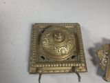 two pieces of brass on a white surface