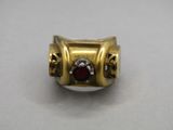 gros plan d'une bague en or avec une pierre rouge