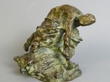 statue of a dog resting on a rock with its head resting on a tree branch