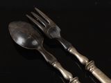 two spoons and a fork on a black table