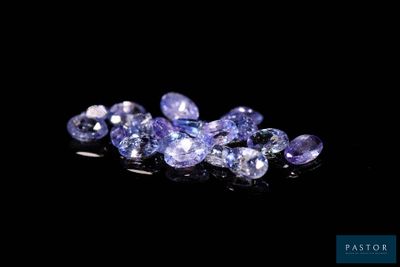 a bunch of purple sapphires sitting on top of a black surface