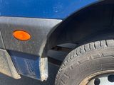 a close up of a blue truck with a flat tire