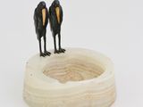 two birds that are standing on top of a bowl