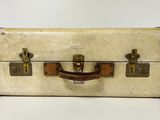 an old suitcase sitting on top of a white table next to a white wall