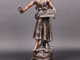 statue en bronze représentant une femme tenant un panier de fleurs, posée sur un socle
