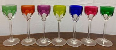 six colorful wine glasses lined up in a row on a wooden table