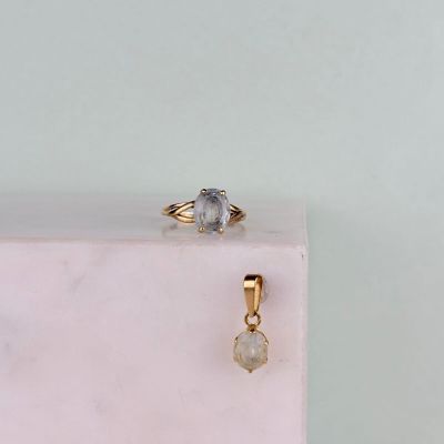 une bague en or sertie d'un diamant blanc posée sur un bloc de marbre rose