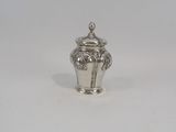 un petit vase en argent posé sur une surface blanche, sur fond blanc