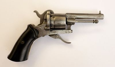 gros plan d'un revolver sur une surface blanche