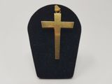 a gold cross pendant on a black velvet stand