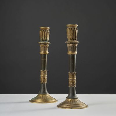 une paire de bougeoirs anciens en laiton posés sur une table blanche
