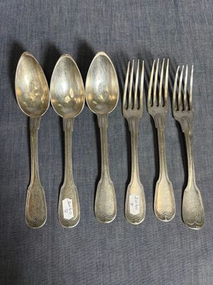 six cuillères en argent et une fourchette sont alignées sur une table