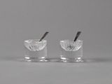 une paire de salières et poivrières en verre transparent contenant chacune une cuillère
