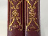 deux livres rouges ornés de motifs dorés, posés l'un à côté de l'autre