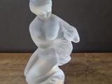 a glass figurine of a woman sitting on a table