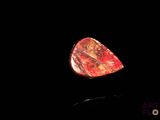 a close up of a red stone on a black surface