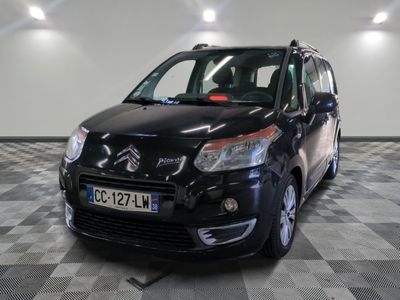 La petite camionnette noire est garée sur un sol en carrelage à damier.