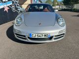 une Porsche argentée garée devant un immeuble dont le mur est recouvert de graffitis