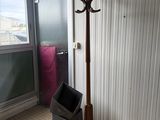 a coat rack and trash can in the corner of a room