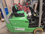 a green forklift with a seat on it in a warehouse