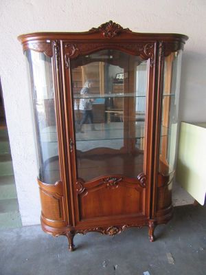 a wooden cabinet with a glass door in the corner of the room