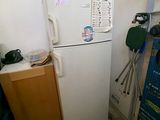 un réfrigérateur blanc dans une petite cuisine, avec une boîte bleue posée dessus