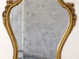 a gold mirror hanging on the wall in a room