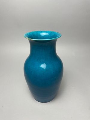 blue vase with a gold rim sitting on a white surface