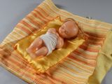 une poupée allongée sur une couverture posée sur une table