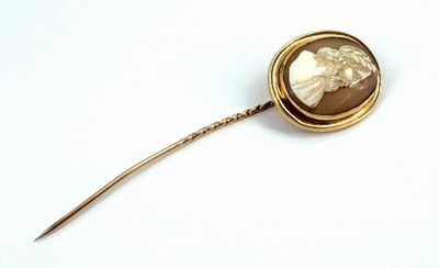 a gold brooch with a picture of a woman on it