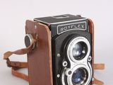 an old camera with a leather case and strap on a white surface