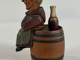 a figurine of a man sitting on a barrel with a bottle of wine