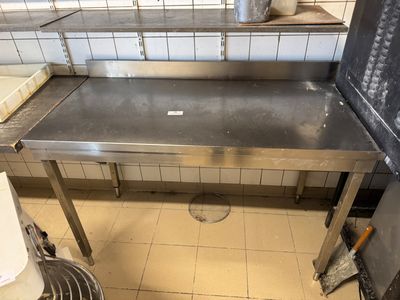 a stainless steel table in a kitchen with a trash can
