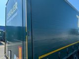 a green semi trailer parked in a parking lot