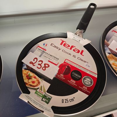 trois poêles exposées dans un magasin, avec leurs étiquettes de prix