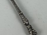 a silver spoon with a handle on a white surface