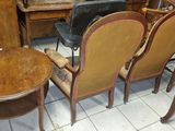 several chairs and a table in a room with a lot of furniture in the background