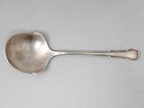 une cuillère ancienne en argent à long manche posée sur une surface blanche
