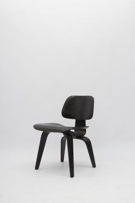 une chaise Eames noire avec une assise en cuir noir sur fond blanc